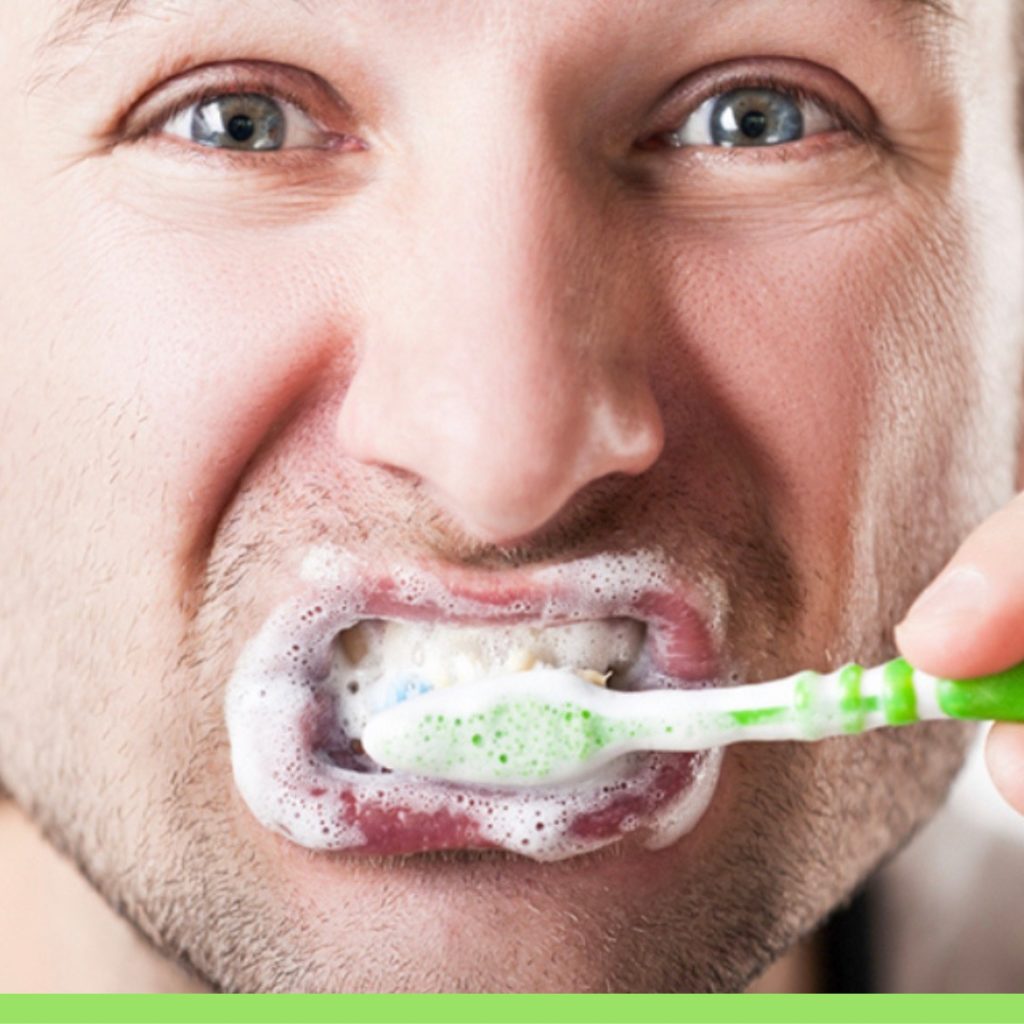 pesona uomo che lava i denti con dentifricio su spazzolino verde e bianco