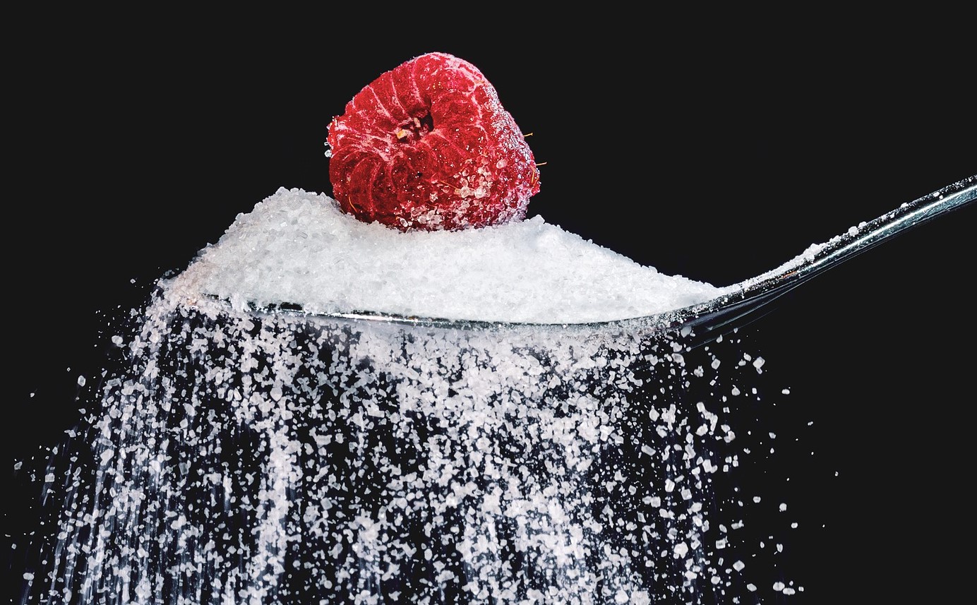 lo zucchero su un cucchiaio e con una mora. lo zucchero scende a pioggia dal cucchiaio