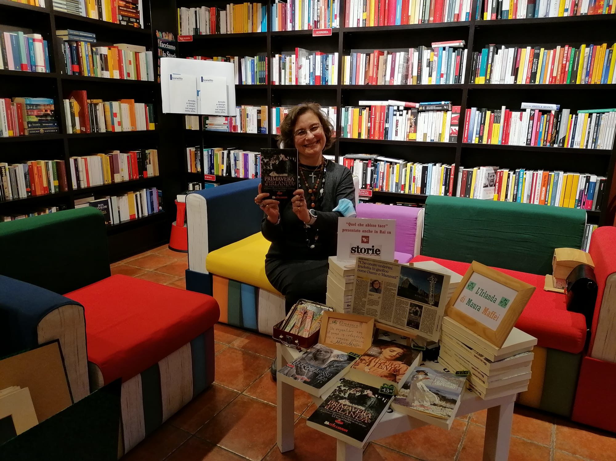 Maura Maffei presenta il romanzo primavera d'Irlandaseduta in mezzo a scaffali di libri 