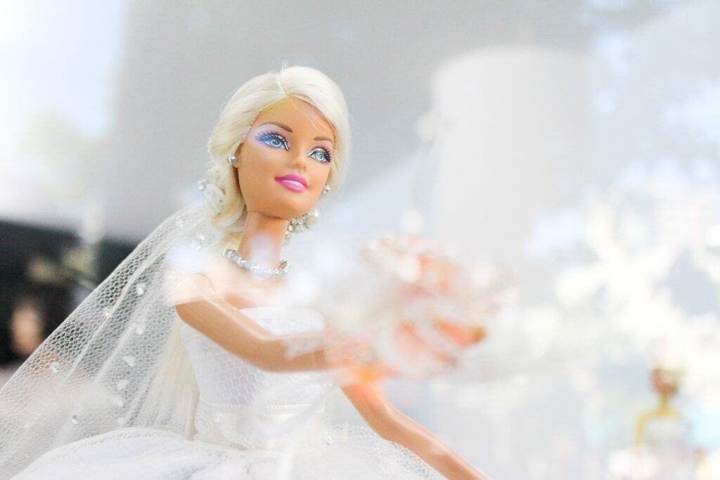 Una bambola Barbie vestita da sposa con abito lungo, velo e un bouquet di fiori in mano