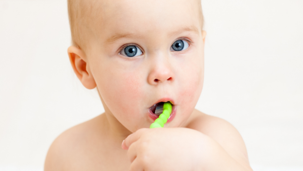 Bambino piccolo che si spazzola i denti con spazzolino verde
