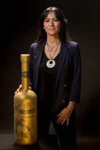il limoncello pallini  - la bottiglia dipinta in oro con le scritte verdi e di fianco sulla destra l'artista Yuriko che l'ha disegnata. Una bella donna con capelli neri, vestita di nero con una vistosa collana con un ciondolo rotondo