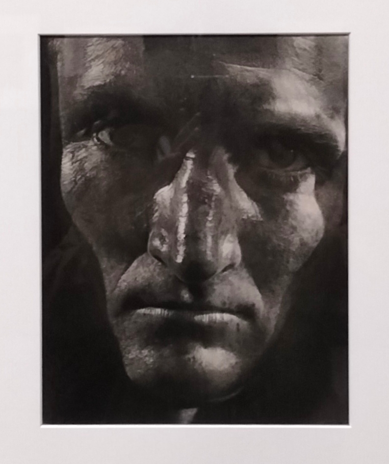 MOMA- foto dello stesso volto dell'immagine precedente. Il fotografo cattura il viso frontalmente, la luce diretta evidenzia le parti spigolose della faccia dando così un'aria minacciosa al soggetto.