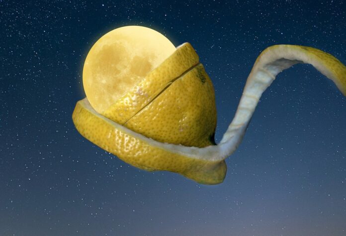 sfondo: un cielo stellato. Primo piano: una fetta di limone con la buccia forma un cucchiaino e sopra la fetta mezzo limone che raccoglie la luna