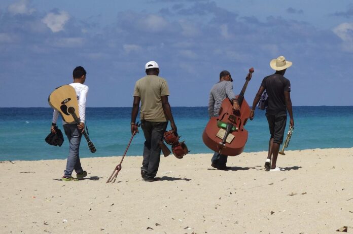 un posto al sole - un fgruppo di musicisti sulla spiaggia, fotografati di spalle