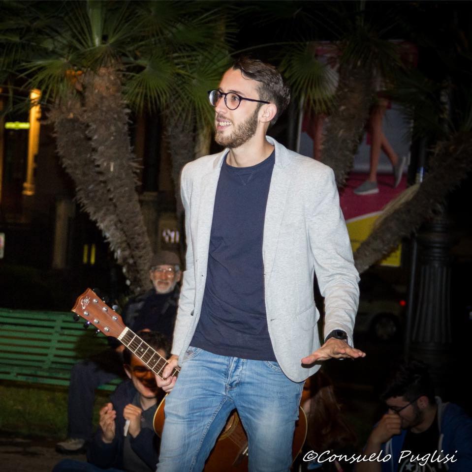 Insieme tra le righe - Samuele Carcagnolo indossa jeans, t shirt blu e giacca grigia. Ha barba, occhiali e capelli neri corti