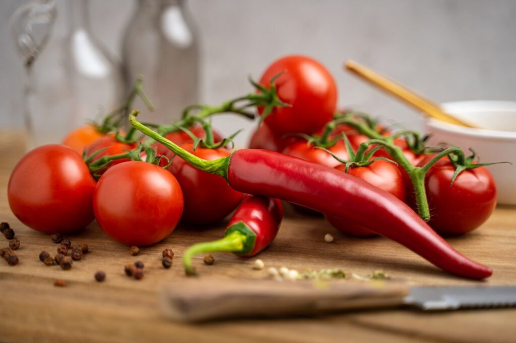 la dieta dei cinque colori: un tagliere di legno con sopra pomodori e peperoncini rossi