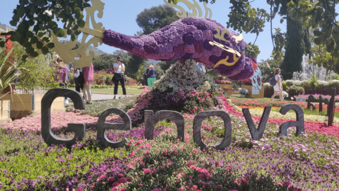 Euroflora 2022: storie di fiori, di bellezza e di passioni in foto una composizine fatta tutta con giori viola raffigurante un pesce sopra un prato con la scritta Genova