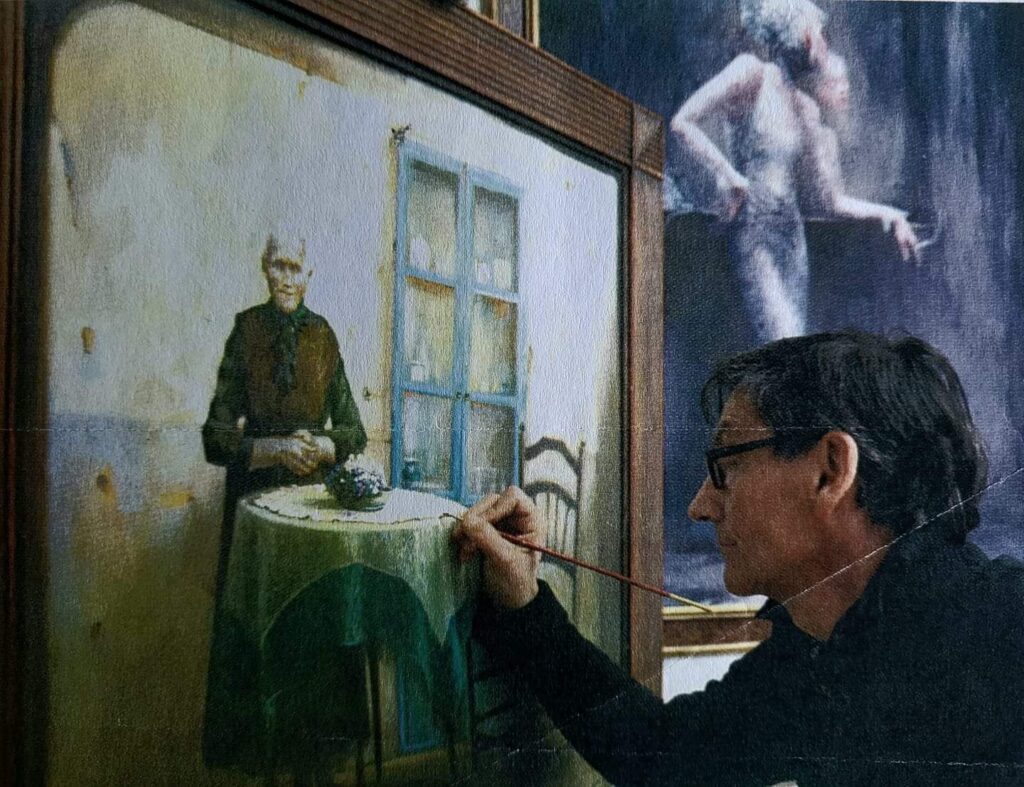 Davide De Agostini mentre dipinge nel suo atelier una donna un piedi davanti un tavolo rotondo 