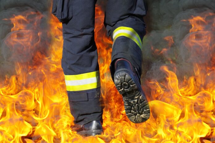 Vigili del fuoco - foto molto suggestiva con inquadratura sugli scarponi di un vigile del fuoco che cammina in mezzo al fuoco