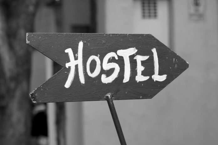 Ostello, salento, camminatori, turismo, cultura, progetto. Foto in bianco e nero con un cartello con scritto Hostel in vernice bianca.