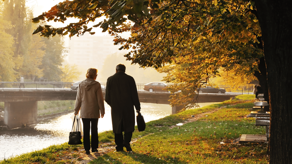 Anziani soli in una passeggiata in un parco autunnale con riva fiume 