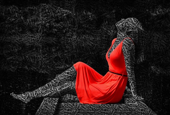 ciclo mestruale - nella foto con sfondo nero, una ragazza è seduta con le gambe leggermente piegate e le braccia appoggiate dietro la schiena, il capo recrinato all'indietro. indossa un vestito rosso scollato. Il suo corpo nero è fatto di scritte bianche