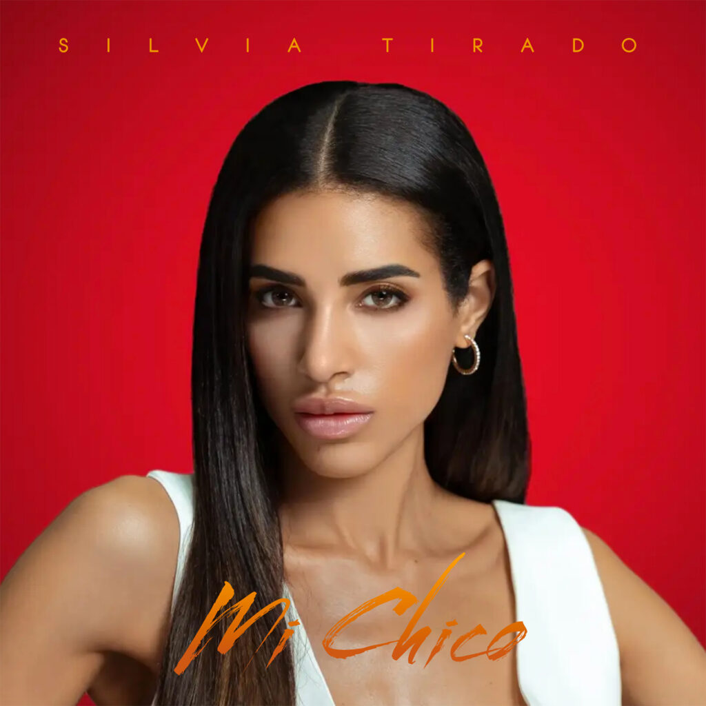 silvia tirado - la copertina di mi chico, che la ritrae in primo piano. capelli neri lunghi, indossa una canotta bianca scollata