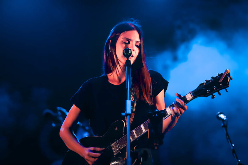 claaire audrin in concerto, vestita di scuro, ha a tracolla una chitarra elettrica nera