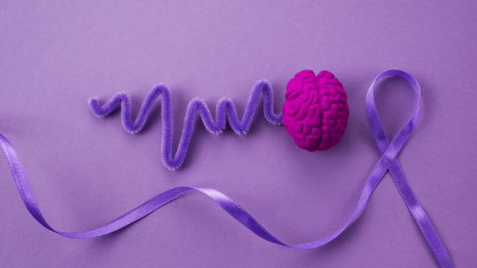 sinbolo della fibromialgia il nastro viola qui insrito su sfondo violetto come batitito cardiaco che esce dal cervello
