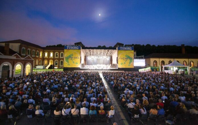 immagini del flowers festival 2021 a collegno, palco giallo con scritte e persone sedute