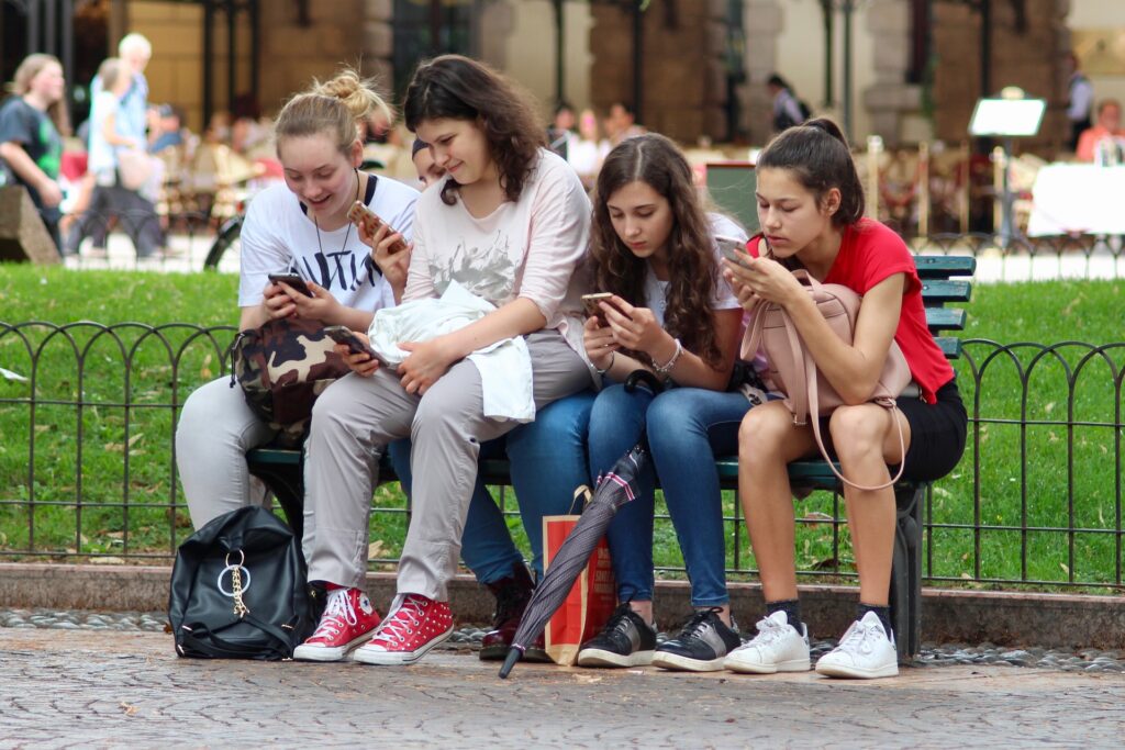violenza domestica . delle ragazzine sono sedute su una panchina e tutte e 4 stanno scrivendo al proprio cellulare