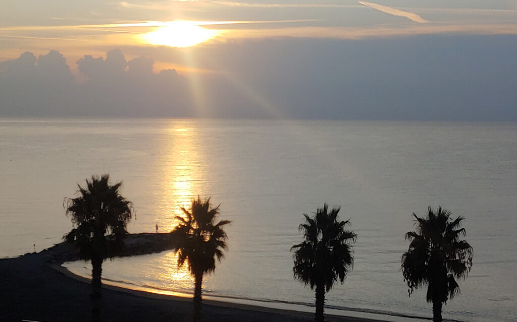 lIGURIA - UNA VEDUTA PANORAMICA DEL MARE AL TRAMONTO CON LE PALME SULLA SPIAGGIA