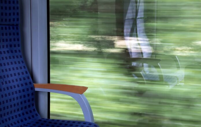 treni gratis Lazio - nella foto il finestrino di un treno con il paesaggio sfocato dalla velocità e nel vetro si riflette ilposto vuoto del passeggero