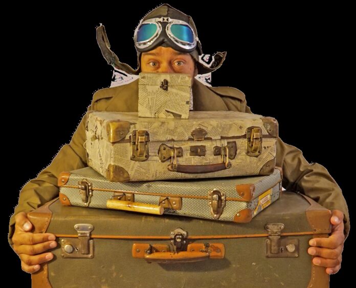 Frangenti - Cetara FEstival - nella foto un uomo con un cappello da antico aviatore tiene in mano delle valige disposte a piramide