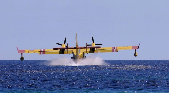 Un canadair antincendio in azionegiallo mentre carica acqua sul mare