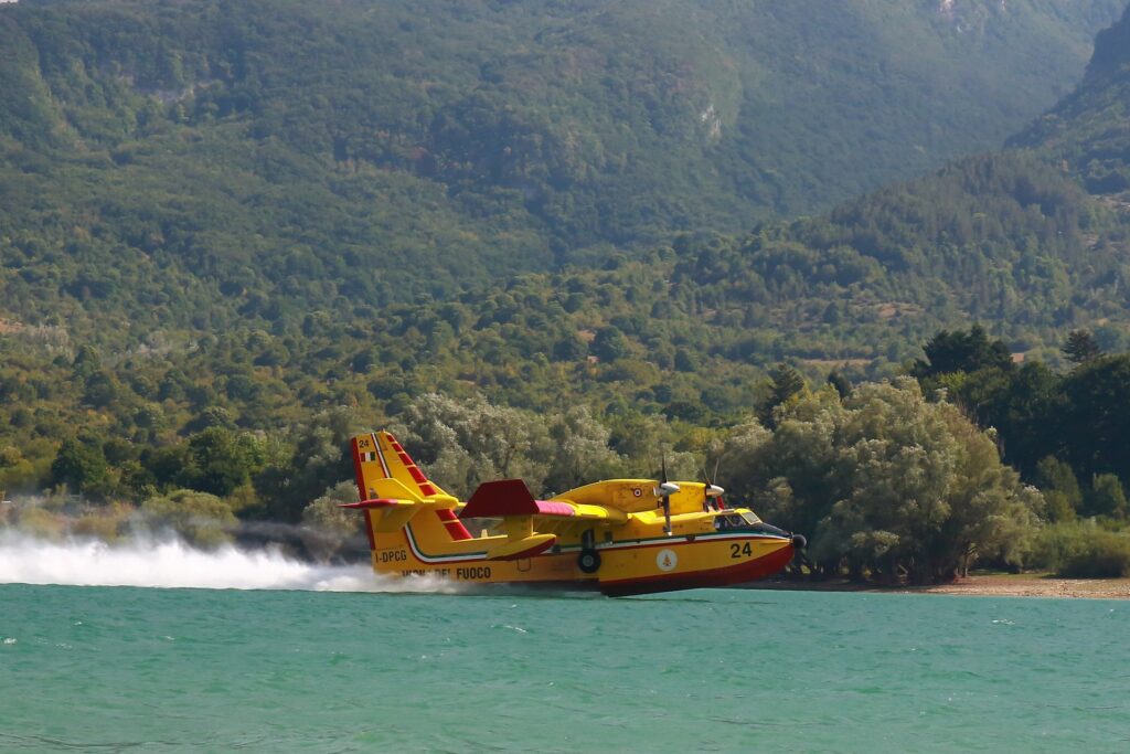 incendi - Un canadair antincendio in azionegiallo mentre carica acqua sul mare