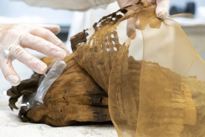 Una ricercatrice sta sollevando delle bende da una mummia