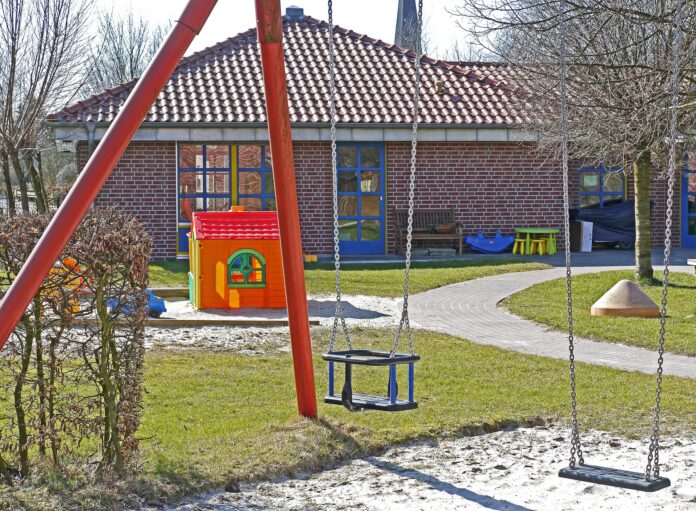 caro bollette - nella foto una scuola materna vuota con davanti un giardino e delle altalene