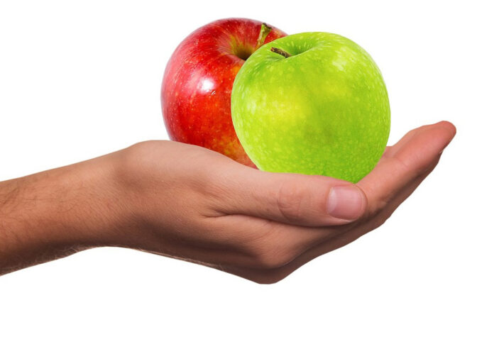 una mela rossa e una verde in una mano di donna
