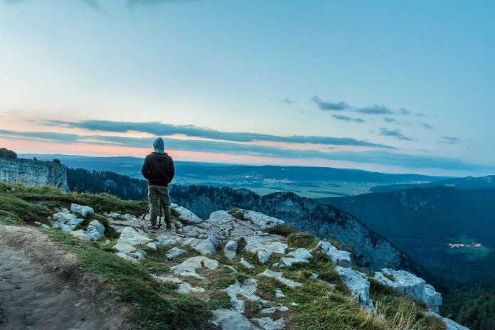 paranormale - un uomo che indossa una felpa scura e pantaloni chiari da tuta, di spalle mentre guarda il panorama montano