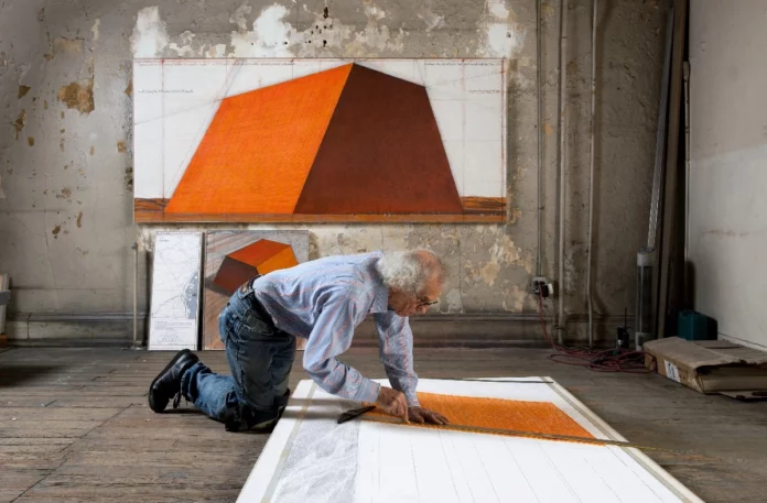 Christo nel suo studio in preparazione di mastaba con progetti arancioni su carta