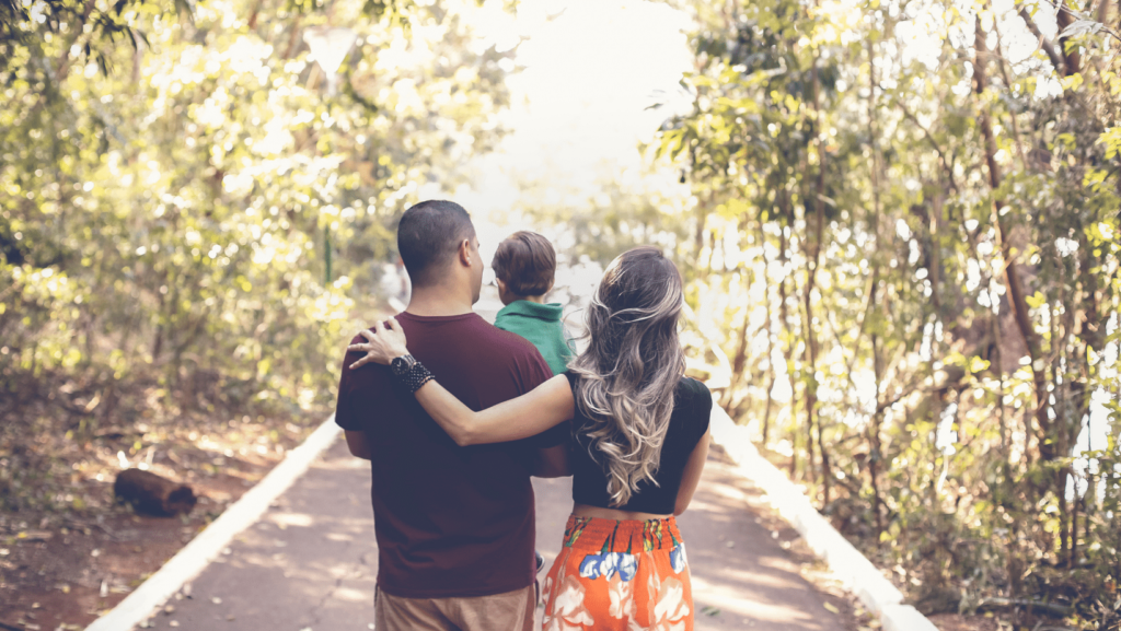 una famiglia di spalle con papa mamma e bambino si allontanano su un sentiero