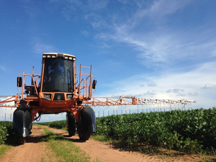 Agricoltura europea a rischio: no alla riduzione dei fitofarmaci - nella foto un trattore attraversa un campo cospargendolo di pesticidi con un annaffiatoio meccanico
