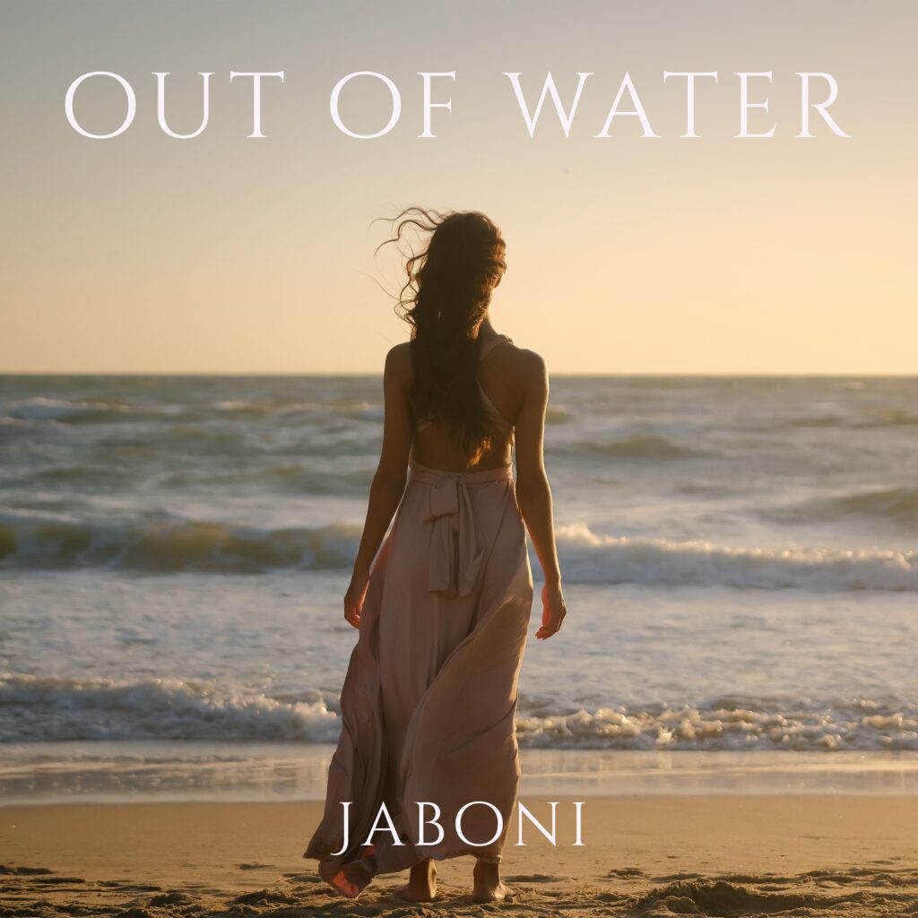 out of water - una donna di spalle, sulla spiaggia al tramonto, che indossa una sottoveste chiara
