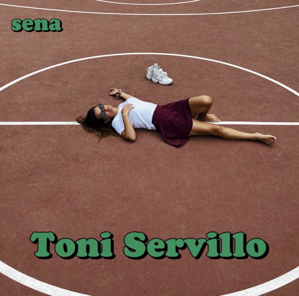 toni servillo - sena sdraiata su un campo da tennis in terra rossa, indossa maglia bianca e gonna granata