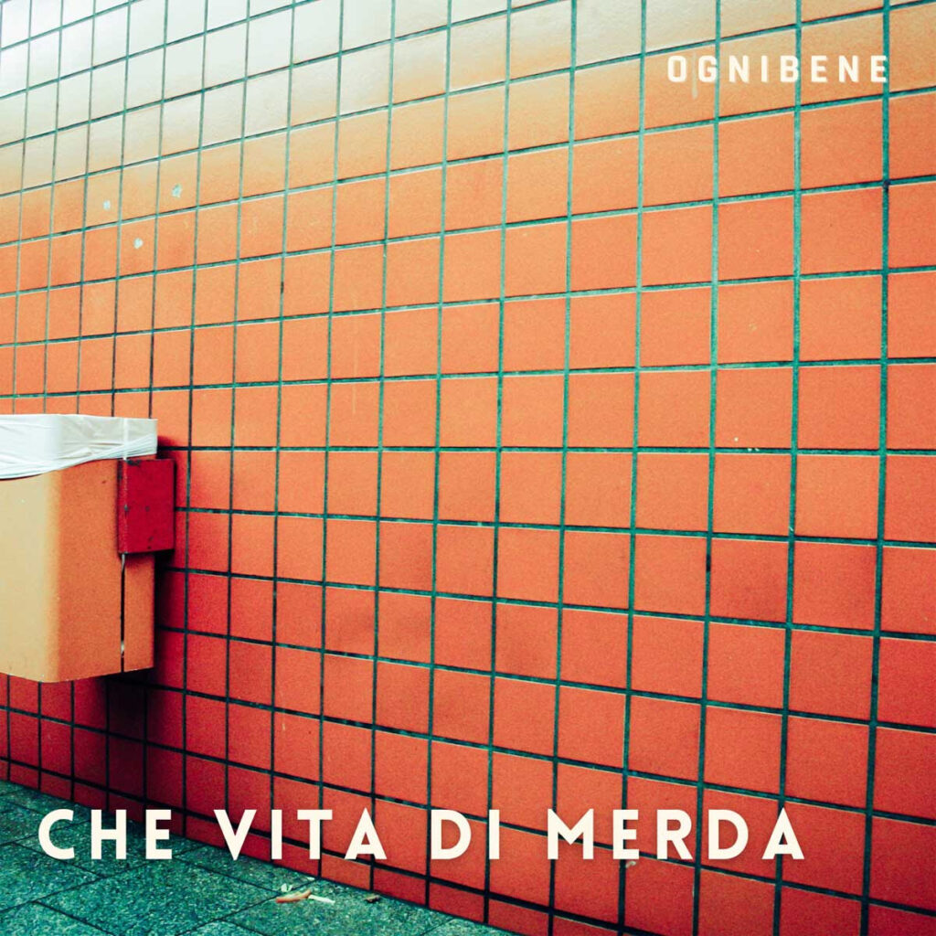 ogniben - la copertina del singolo "che vita di merda", che raffigura un muro di piastrelle arancioni, con appeso un cestino dei rifiuti