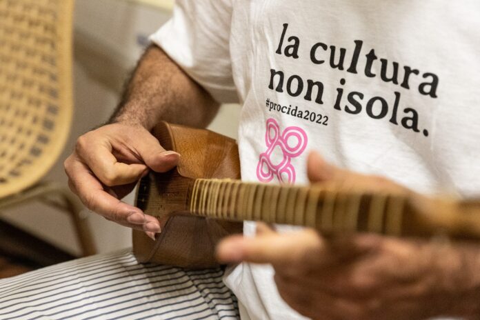 un uomo suona uno strumento etncio con la scitta la cultura non isola nel progetto amih
