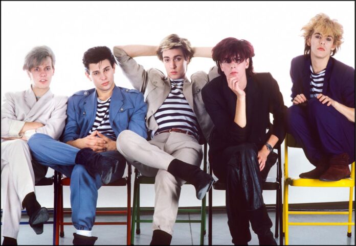 Duran Duran - nella foto i cinque componenti della band sono seduti e ognuno ha un look tipico anni 80