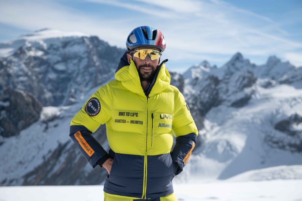 omar di Felice in posa di fornte a montegne innevate con giacca giala e casco blu