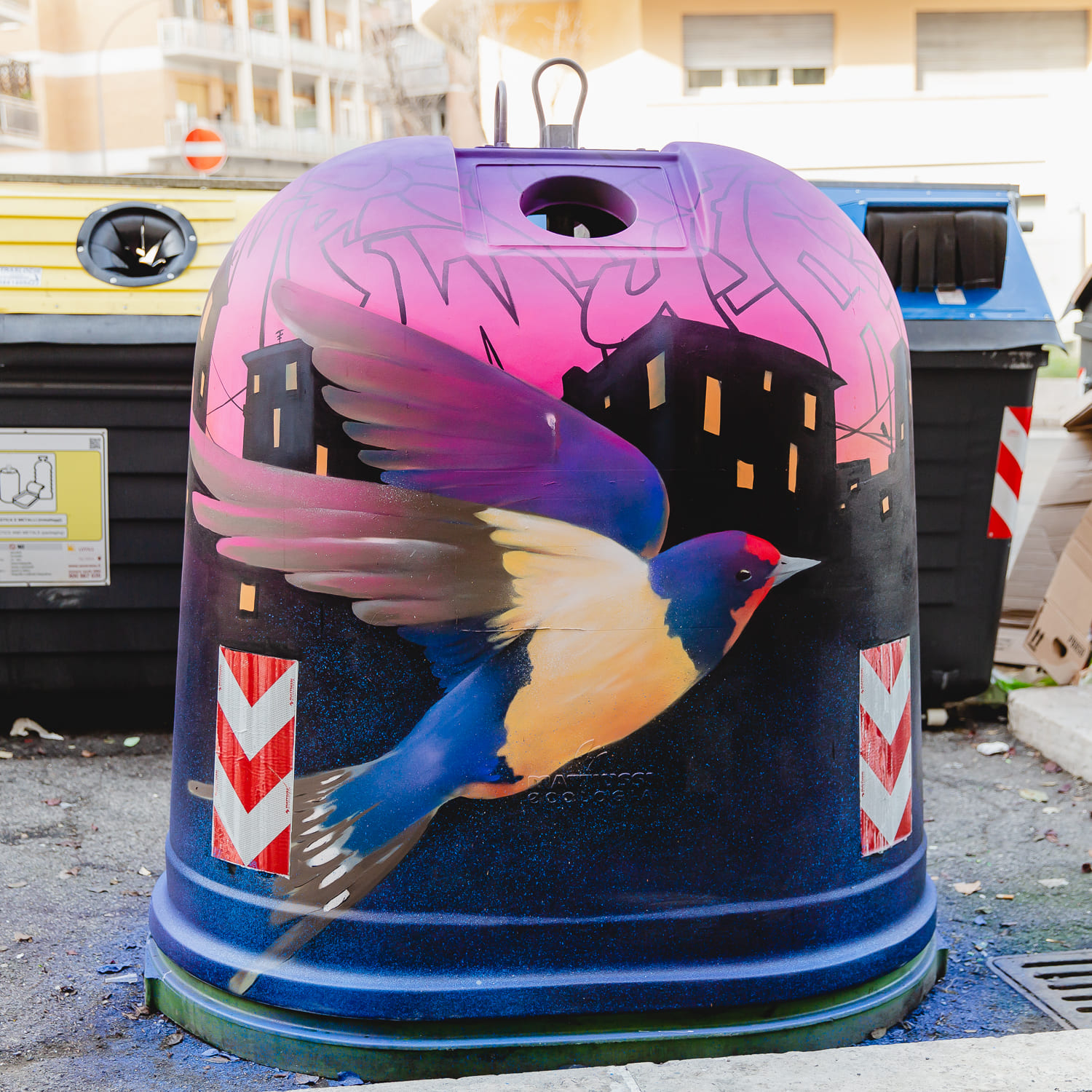 open gau - una campana del vero con disegnato un uccello con ali colorate , coda e collo blu, becco rosso.