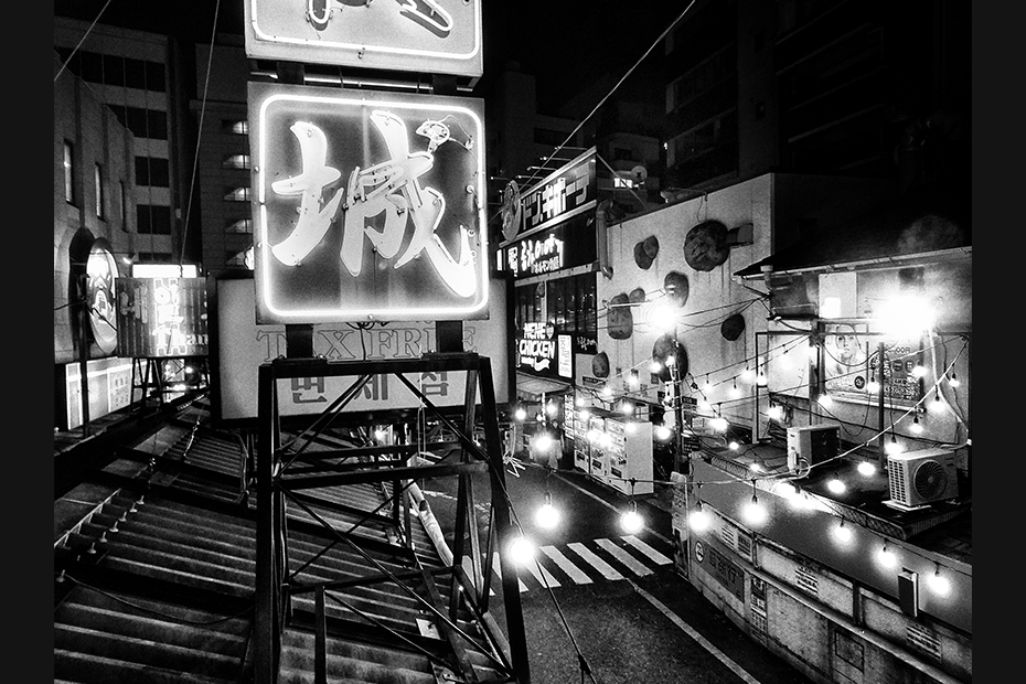 immagini bianco e nero metropoli di tokyo con insegne in primo piano caratteri giapponesi