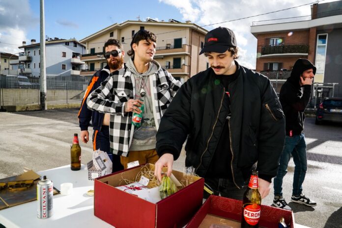 lovegang126 - i rapper del collettivo davanti a un tavolo con sopra una scatola e delle bottiglie di birra