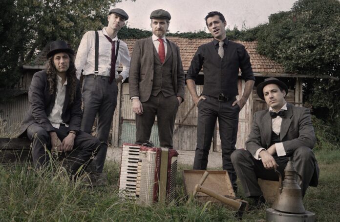 meneguinness - la band milanese, 5 componenti, fotografata in abiti old style, fuori da una vecchia cascina di campagna