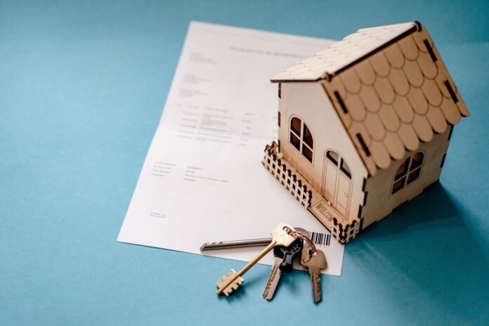 Mutui immobiliari: nella foto una casetta di legno appoggiata su un tavolo. sul tavolo ci sono anche delle chiavi e un foglio di carta