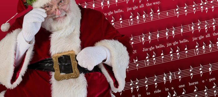 canzoni natalizie - babbo natale in primo piano, sullo sfondo uno spartito musicale rosso con su scritta una canzone di natale