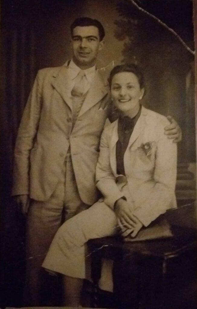 due sposi seduti vicini il marito in piedi la moglie in spezzato bianco seduta