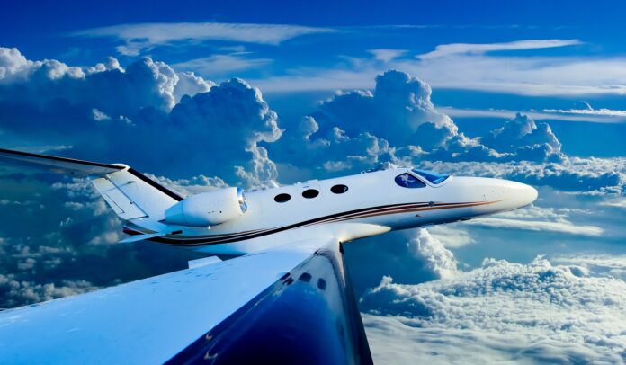World Economy Forum . nella foto un jet privato bianco con una striscia rossa lungo il fianco dell'aereo, vola in mezzo a nuvole bianche