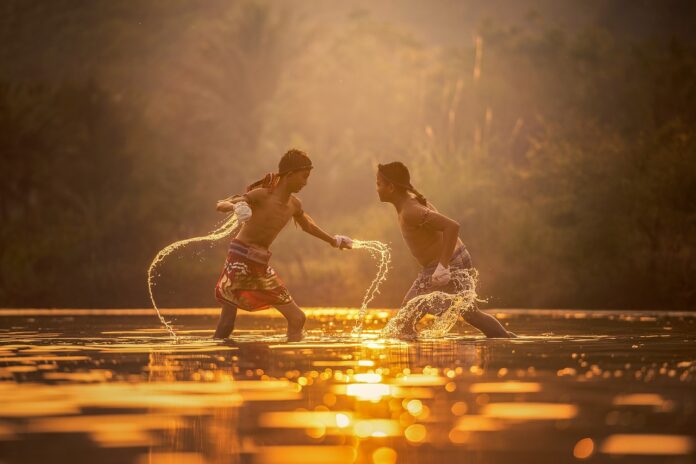 children - due giovani ragazzi asiatici intenti a lottare nell'acqua