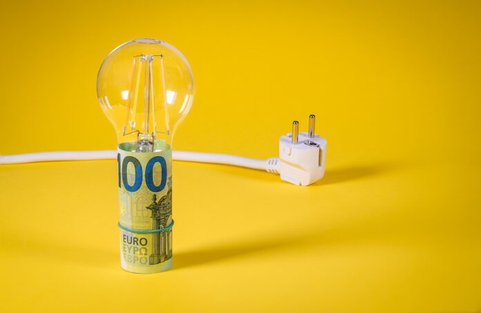 provvedimenti cautelari - nella foto su sfondo giallo una lampadina con la base fatta con un rotolo di banconote da cento euro e un filo con la spina